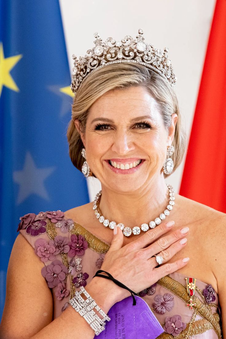 a woman wearing a tiara standing in front of flags