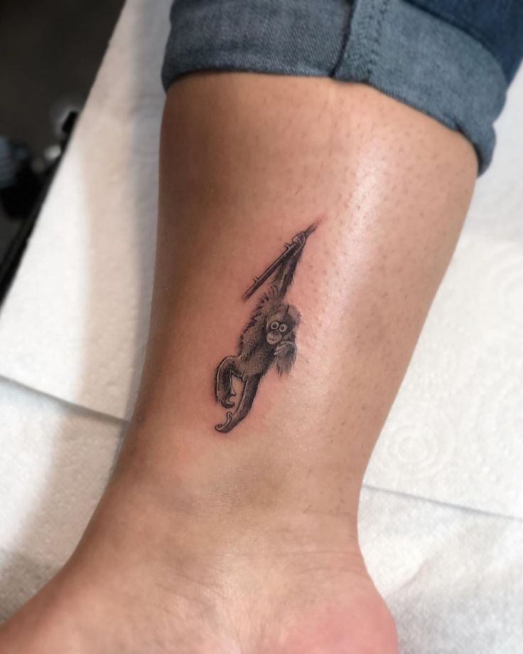 a small tattoo on the ankle of a woman's foot, with a squirrel holding an umbrella