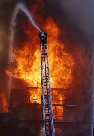 a firetruck is spraying water on a building that's engulfed in flames