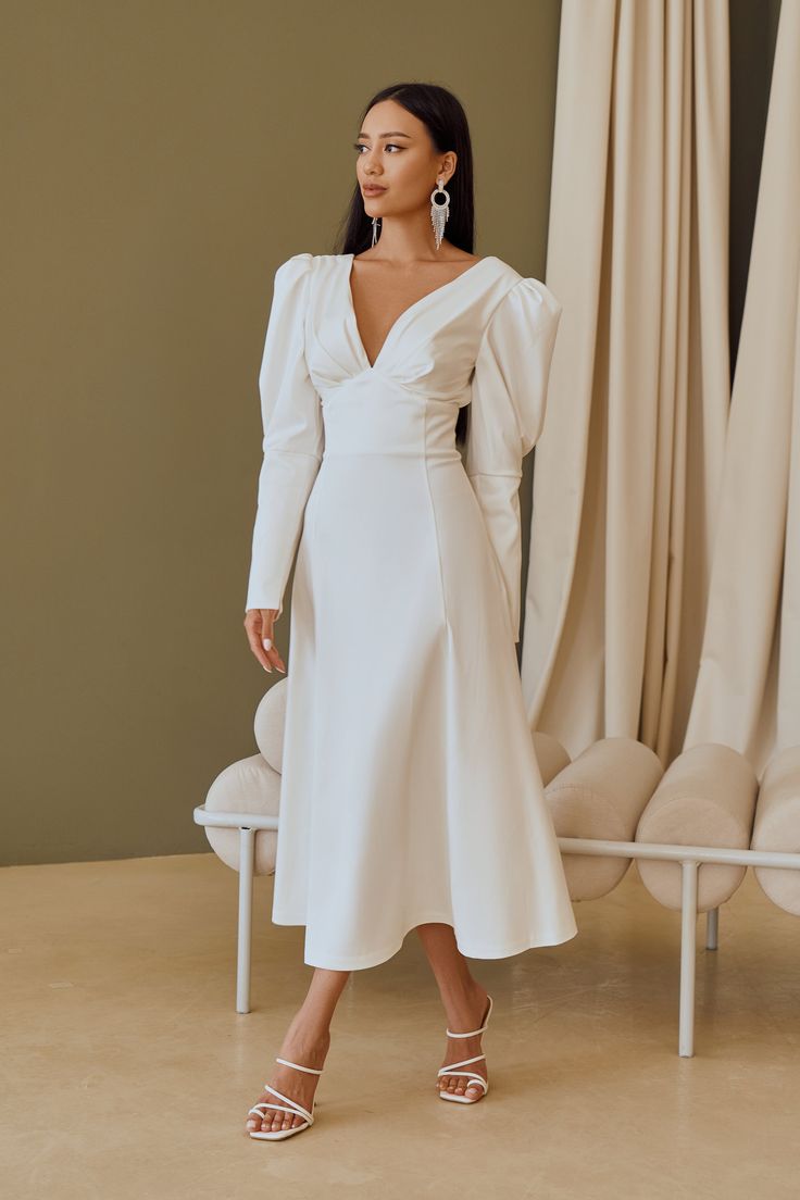 Fabric: Heavy Satin Cotton 50%, Polyester 50% V-neck dress Puffed sleeves Long sleeves Bow on back detail Zipper on back Dress lenght: 125 cm/ 49,2 inSleeve length: 68 cm/ 26,7 in Colors: White, Sky-Blue, Dusty Pink Elegant V-neck Midi Dress With Elastic Sleeves, Long Sleeve Ruched Midi Dress With Fitted Bodice, Ruched Long Sleeve Midi Dress With Fitted Bodice, Fitted V-neck Puff Sleeve Dress For Wedding, Chic V-neck Long Sleeve Dress With Gathered Sleeves, Elegant Midi Dress With Fitted Bodice And Bishop Sleeves, Elegant Fitted V-neck Dress With Gathered Sleeves, Formal Midi Dress With Balloon Sleeve And Structured Shoulders, Formal Midi Dress With Structured Balloon Sleeves