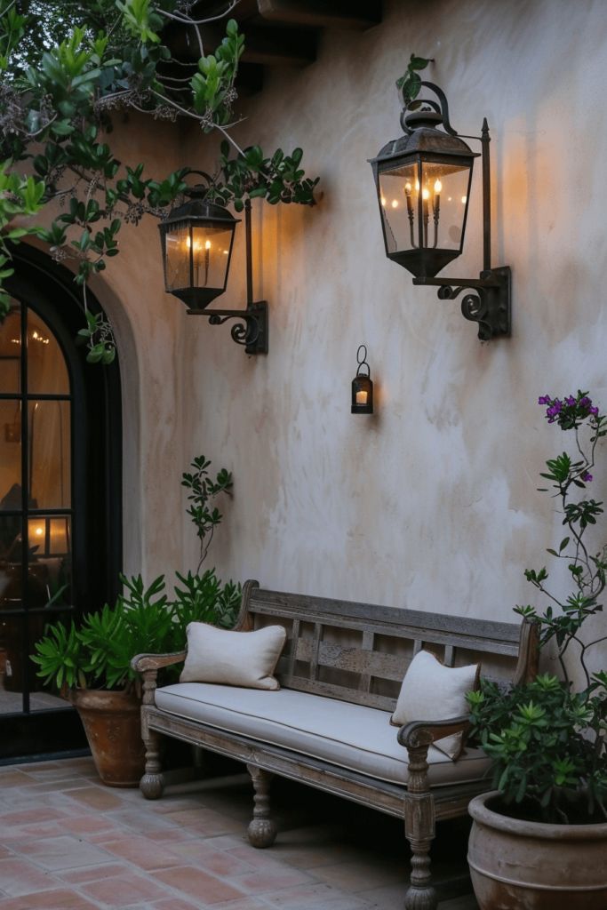 a bench sitting in front of a building with potted plants and lights on the wall