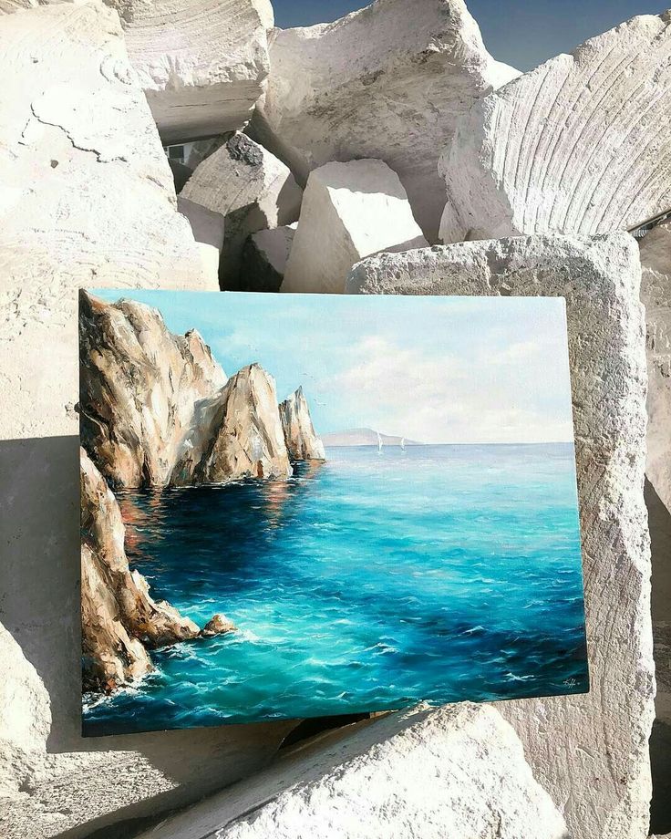 a painting is displayed on some rocks by the ocean