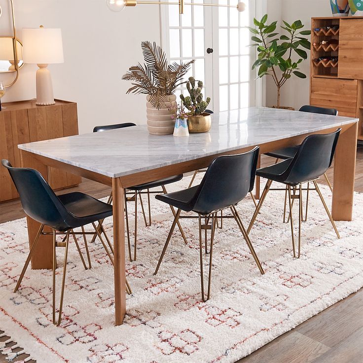 a dining room table with four chairs and a potted plant in the corner on top