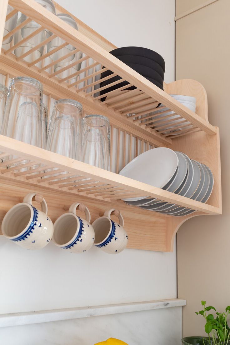 a wooden shelf filled with dishes and cups next to a yellow bowl on top of a counter