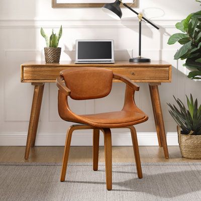 a wooden desk with a laptop on it and a potted plant next to it