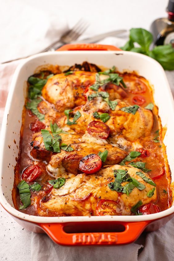 a casserole dish with chicken, tomatoes and spinach in it on a table