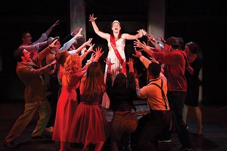 a group of people on stage with arms in the air