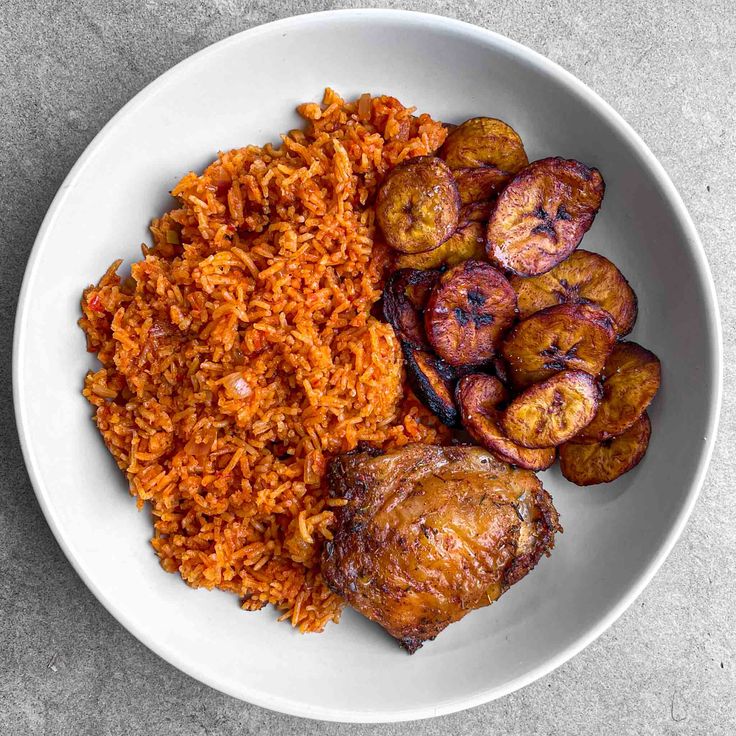 a white plate topped with meat and rice next to fried potatoes on a gray surface