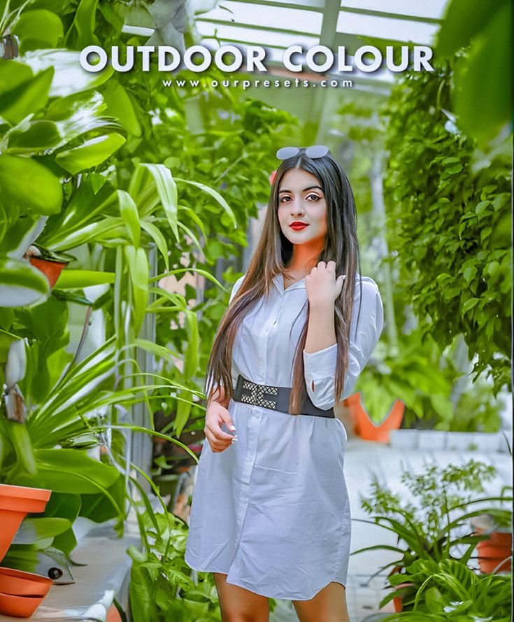 a woman is posing in front of some plants