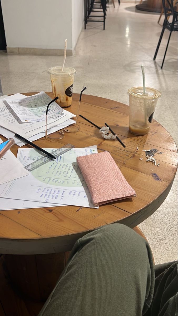 a wooden table topped with papers and glasses