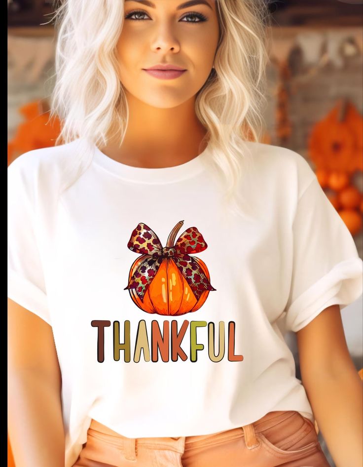 A fall themed T-shirt featuring a beautiful orange pumpkin with a bow and colorful 'thankful' lettering. Perfect for the autumn season, Thanksgiving, and harvest celebrations. Provides a cozy and festive vibe, ideal for anyone looking to add a touch of gratitude to their wardrobe.Great for a Fall lovers! Product features - Made from 100% ring-spun cotton for a lightweight and comfortable feel - Classic fit with crew neckline suitable for any occasion - Ethically grown and harvested US cotton for sustainability - Variety of fabric blends available for different color options - Tear-away label for added comfort and customization Care instructions - Do not dryclean - Machine wash: warm (max 40C or 105F) - Do not bleach - Tumble dry: low heat - Iron, steam or dry: low heat Orange Letter Print T-shirt For Fall, Orange T-shirt With Letter Print For Fall, Fall Season T-shirt Gift, Fall Gift T-shirt With Short Sleeves, White T-shirt For Fall Season Gift, White T-shirt For Fall Gift, Short Sleeve T-shirt For Fall Gift, White T-shirt As A Fall Gift, Letter Print T-shirt As Fall Gift