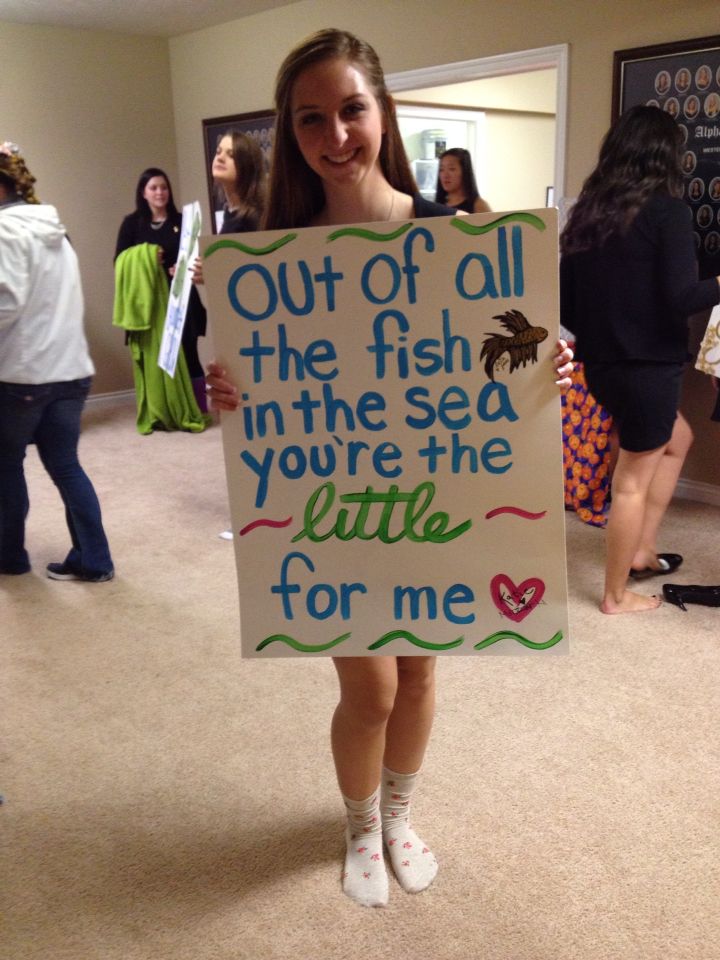 a girl holding a sign that says out of all the fish in the sea you're the little for me