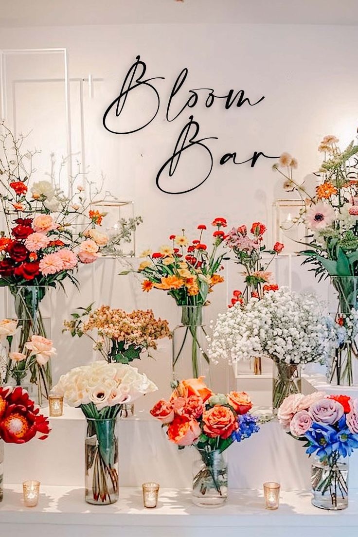 there are many vases with flowers on the table in front of the sign that says bloom bar