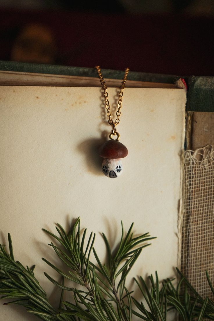 a necklace with a skull on it hanging from a tree branch in front of an open book