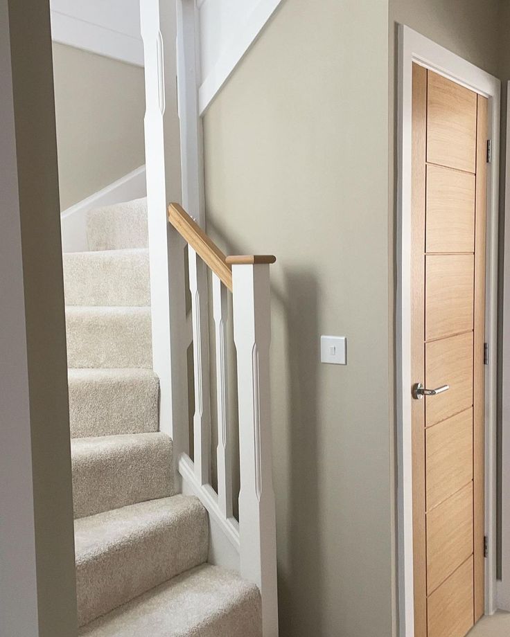 an empty hallway with stairs leading up to the second floor and another room in the background