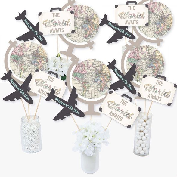 the world awaits cupcake toppers are in a vase with white flowers and an airplane