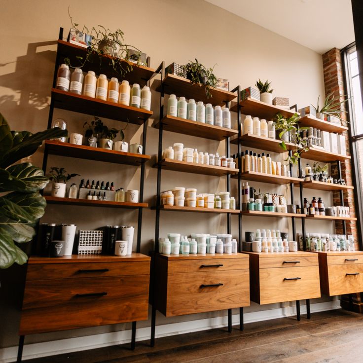 shelves filled with lots of different types of personal care products on wooden shelving next to a large window