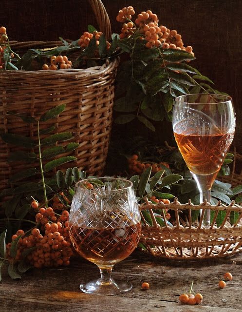 two wine glasses sitting on top of a table next to baskets filled with berries and nuts