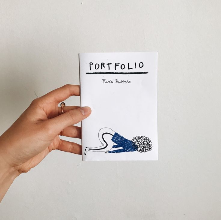 a person holding up a piece of paper with the word portfolio written on it