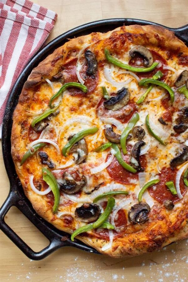 a pizza sitting on top of a pan covered in cheese and toppings next to a red checkered napkin