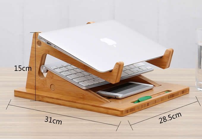 an apple laptop is sitting on a wooden stand with a glass of water and pen