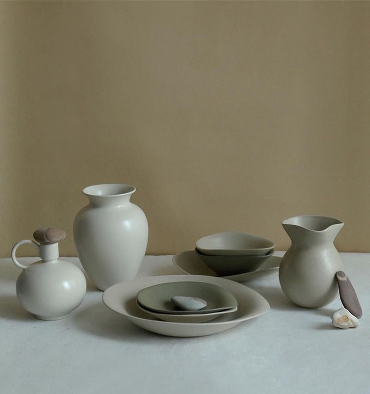 a table topped with plates and vases next to each other on top of a white surface