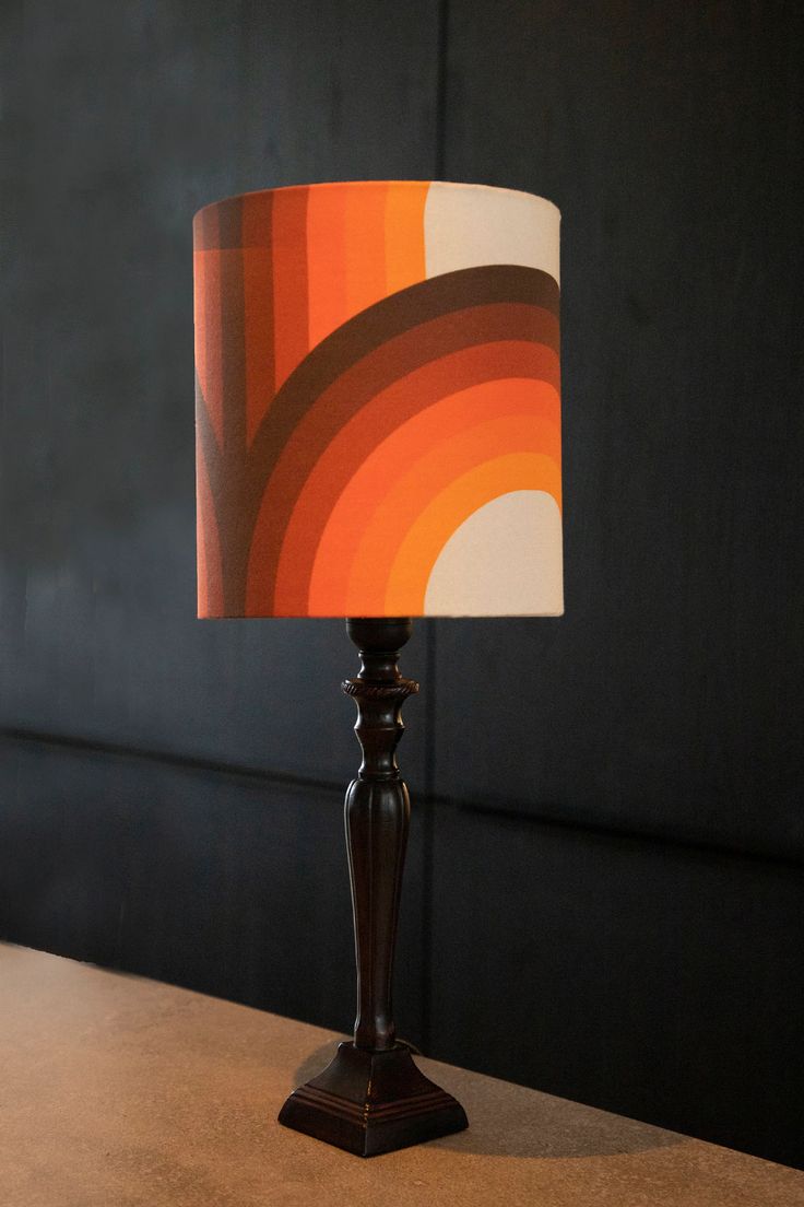 a lamp that is sitting on top of a table with an orange and white shade