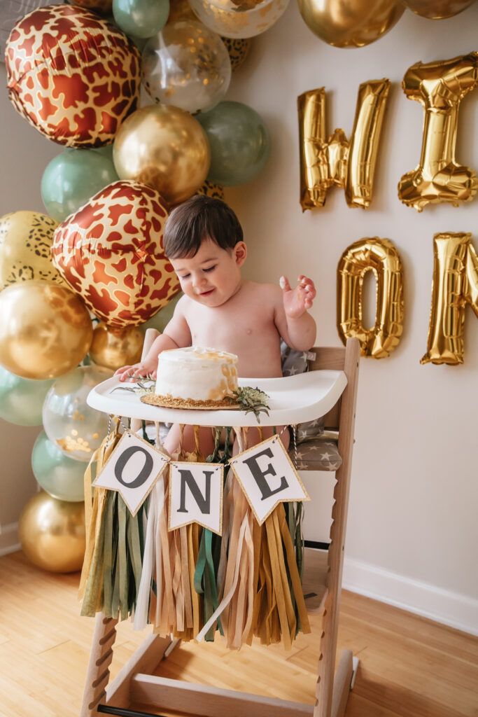 a baby sitting in a high chair with a cake