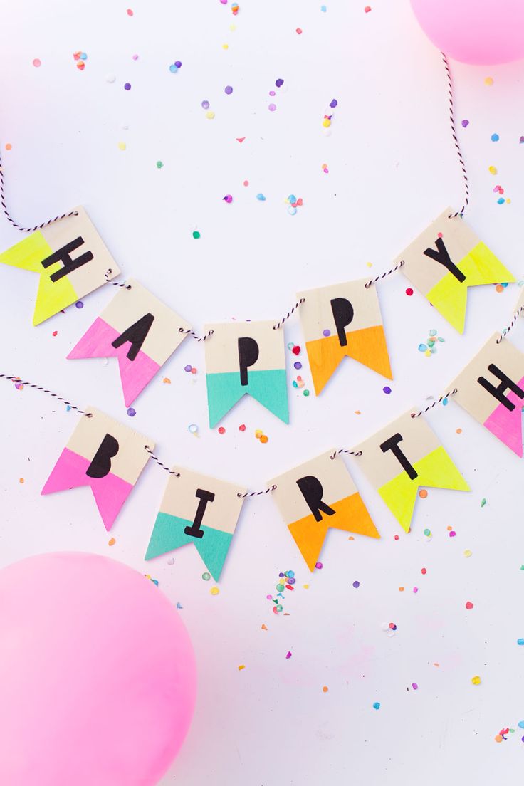 a happy birthday banner with balloons and confetti in the background on a white table