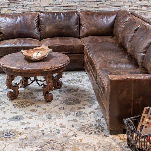 a brown leather sectional sofa sitting on top of a rug next to a coffee table