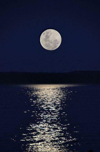 the full moon is shining brightly in the sky over the water's surface at night