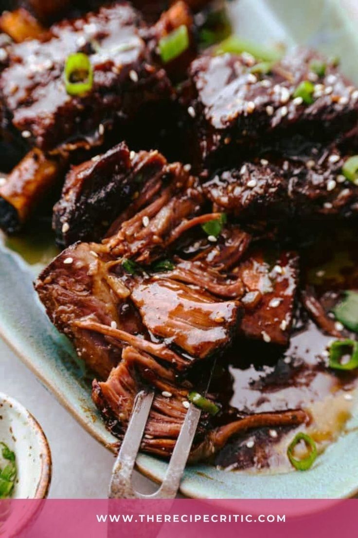 a plate with meat and sauce on it next to two bowls filled with green onions