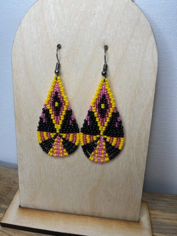 Add some vibrant color to your jewelry collection with these pink, yellow, and black hand beaded earrings! Hand crafted with care and attention to detail, these earrings are sure to make a statement wherever you go! The striking contrast of the bead colors creates a eye-catching and unique design that are sure to complement any outfit. Pink Beaded Drop Earrings, Pink Beaded Teardrop Jewelry, Pink Teardrop Beaded Jewelry, Yellow Teardrop Bohemian Jewelry, Yellow Dangling Beads Earrings, Colorful Beaded Drop Earrings In Yellow, Yellow Beaded Earrings With Tiny Beads As A Gift, Yellow Beaded Earrings With Ear Wire For Summer, Yellow Beaded Earrings With Dangling Round Beads