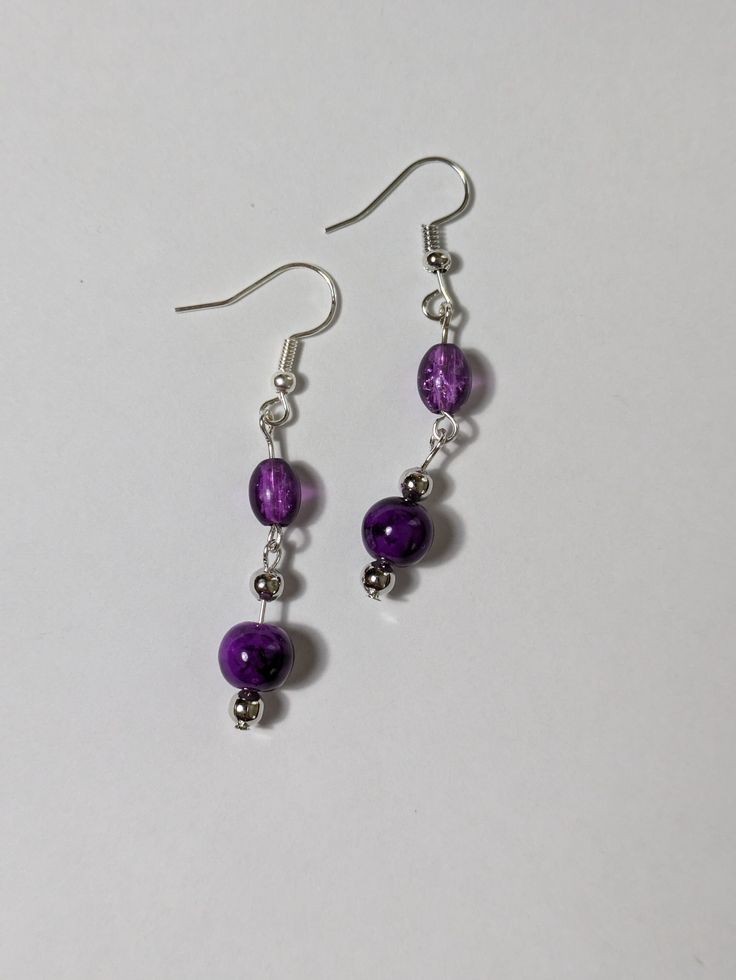 Elevate your jewelry collection with these lovely purple beaded dangling earrings. The round shape and silver tone metal create a chic and sophisticated look, while the hook closure ensures comfortable wear.  Only the best materials are used to create each piece of jewelry  - Glass beads  - Acrylic beads  - Silver tone components Purple Metal Drop Earrings, Purple Round Metal Earrings, Purple Metal Dangle Earrings, Purple Dangle Metal Earrings, Nickel-free Purple Beaded Round Earrings, Purple Drop Crystal Earrings Nickel Free, Nickel Free Purple Crystal Drop Earrings, Elegant Purple Crystal Earrings With Dangling Beads, Purple Metal Earrings