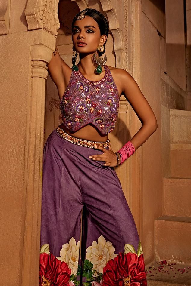 Lilac, multi colored sharara featuring floral designs. Comes with an intricately embroidered padded lilac blouse with heavy tassels and doris.
Components: 2
Type Of Work: Floral
Neckline: Round
Sleeve Type: Sleeveless
Fabric: Raw Silk
Color: Purple,Multi Color
Other Details: 
Backless with tassel tie-ups
Length:
Blouse: 14 inches
Sharara: 44 inches
Model height: 5ft 8inches, wearing size S
Note: All the jewellery worn by the model and the red outfit worn by the other model is not for sale
Occasi Bollywood Style Multicolor Party Tops, Multicolor Tops With Zari Work For Party, Multicolor Blouse For Receptions And Festivals, Multicolor Blouse For Festivals And Receptions, Multicolor Party Tops With Zari Work, Multicolor Semi-stitched Top With Cutdana Detail, Multicolor Semi-stitched Cutdana Top, Semi-stitched Multicolor Cutdana Top, Designer Multicolor Tops With Motifs