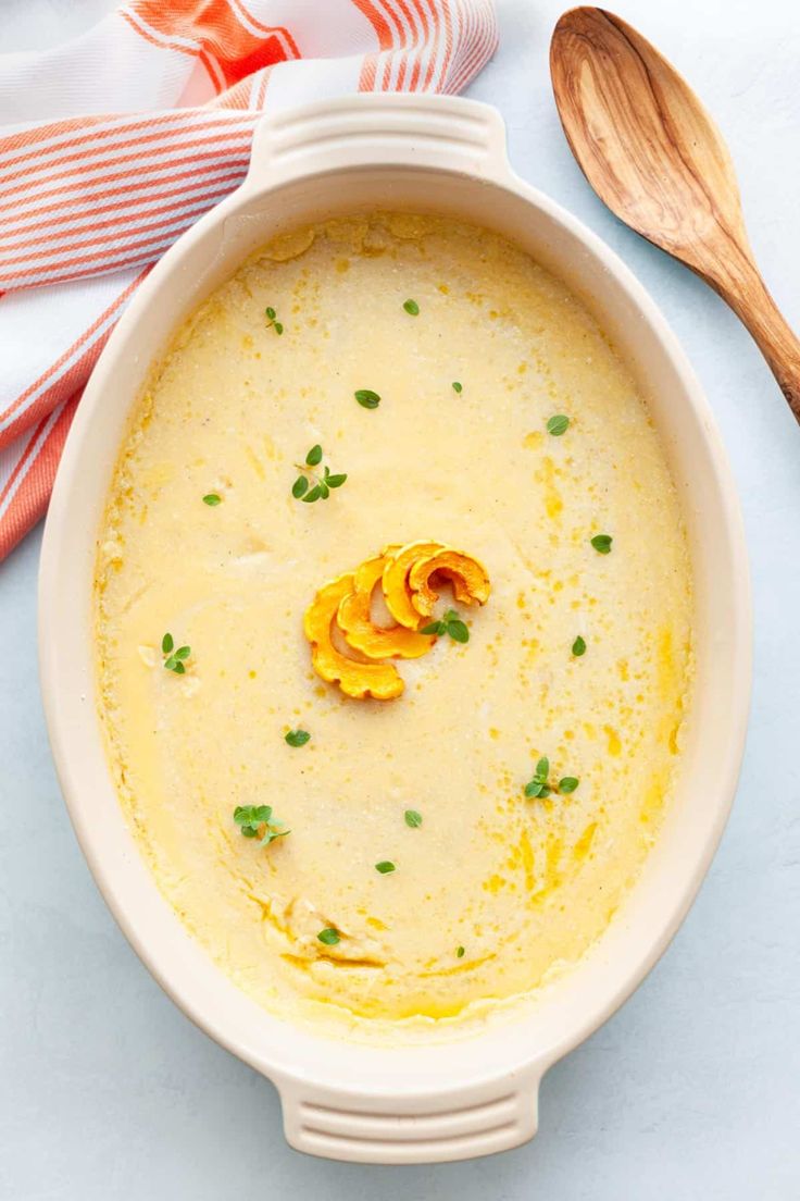 a white bowl filled with soup on top of a blue counter next to wooden spoons