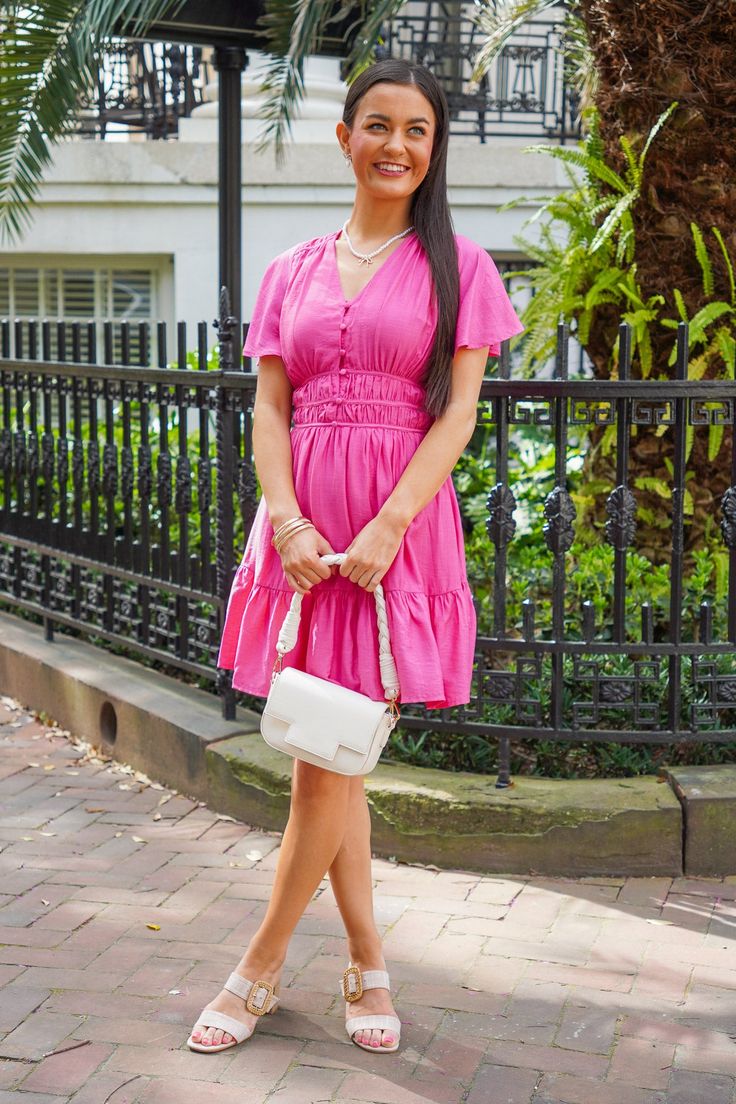 Get ready to turn heads in the Stacie Dress! This pink mini dress is the perfect pop of color for spring. The short flare sleeves and v-neckline with a button up front add a playful touch. With an elasticized waist and tiered mini length, this dress is both comfortable and stylish. Pair it with your favorite heels and pearls for a fun and flirty look! It is lightweight, has a lining, and fits true to size. 85% Rayon, 15% Polyester Brand- Entro Model is 5'5" and is wearing a small Pink V-neck Mini Dress With Ruffle Hem, Casual Pink V-neck Dress For Vacation, Pink Feminine V-neck Dress For Vacation, Feminine Pink V-neck Dress For Vacation, Pink Knee-length V-neck Dress For Spring, Pink Short Sleeve V-neck Dress For Brunch, Pink Feminine V-neck Mini Dress, Feminine Pink V-neck Mini Dress, Pink Feminine Mini V-neck Dress