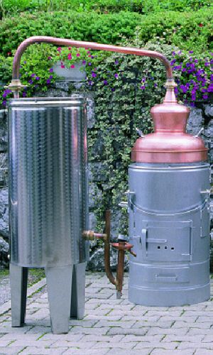 a large metal tank sitting next to a planter on a brick walkway in front of a stone wall