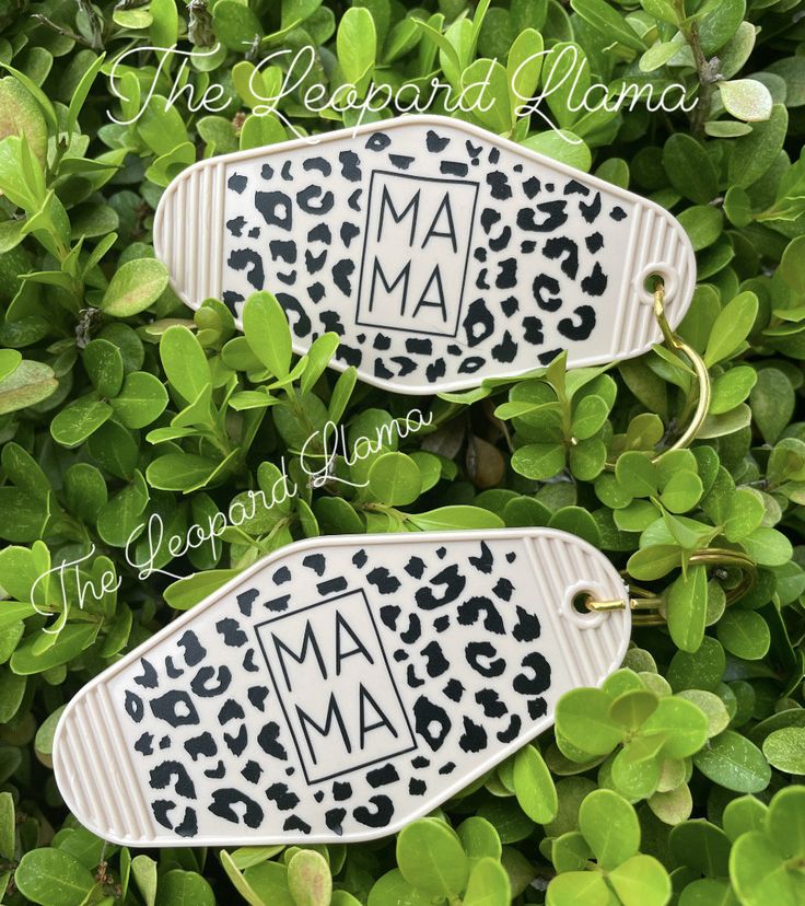 two personalized shoe charms sitting on top of some green leaves with the word mama printed on them