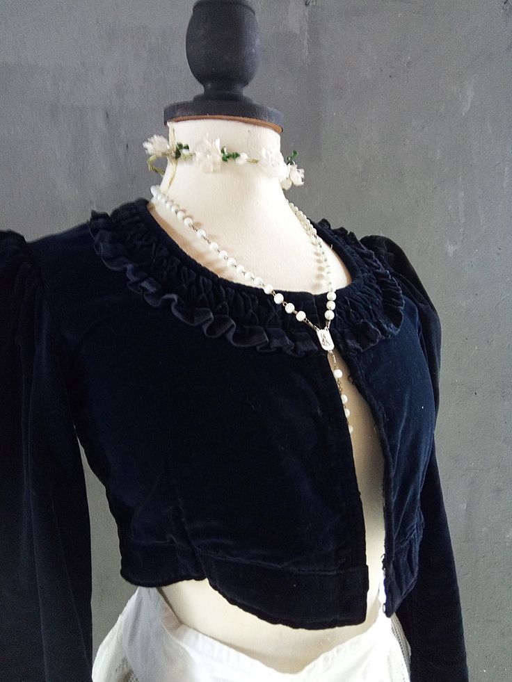 a mannequin wearing a black top and white skirt with pearls on it's neck