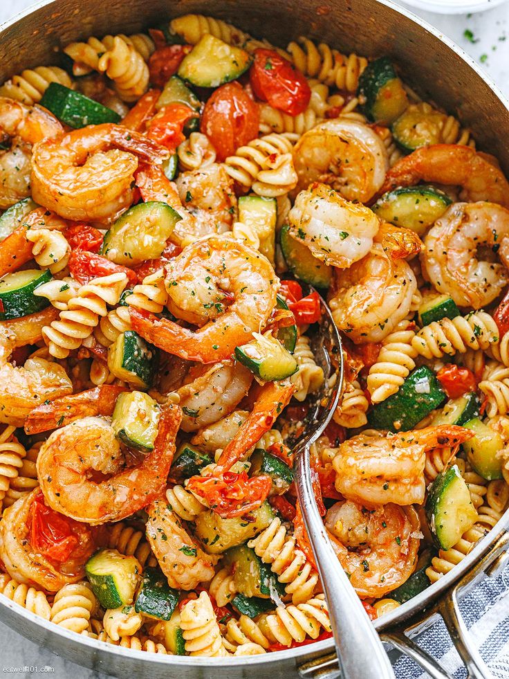 pasta with shrimp, zucchini and tomatoes in a skillet on the table