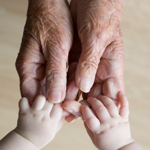 an older person holding the hands of a baby's hand with another child's hand