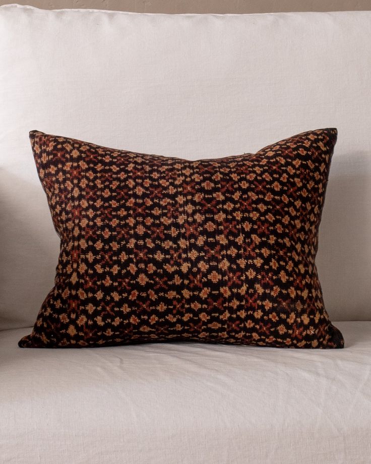 a black and brown pillow sitting on top of a white couch