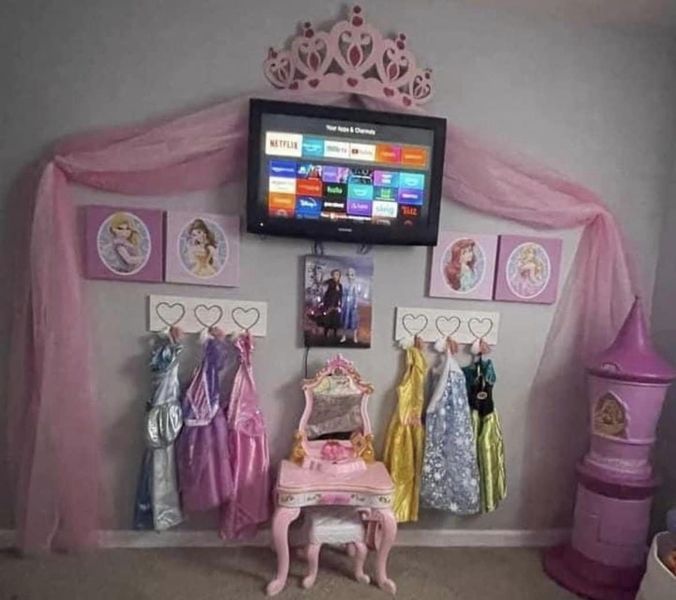 there is a tv that is on in the room with princess dresses and tiaras