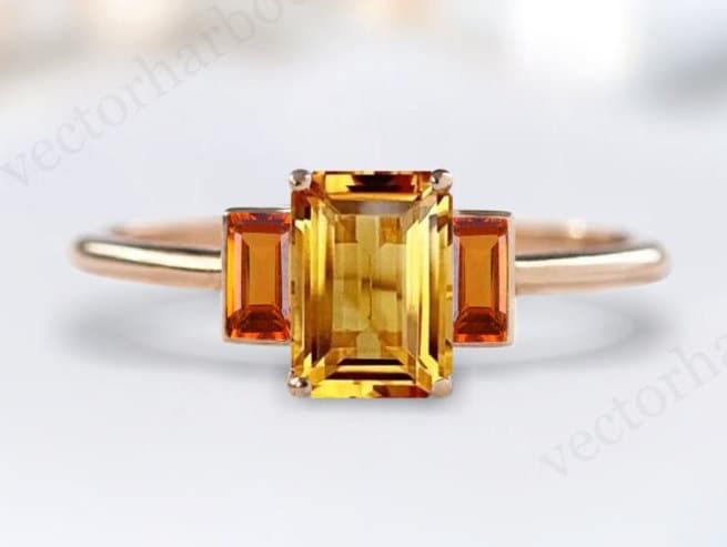 an orange and yellow sapphire ring on a white surface