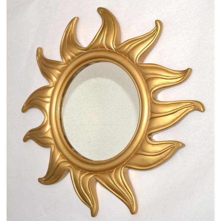 a gold sun shaped mirror on a white wall