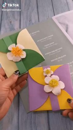 two handmade cards with flowers on them being held by someone's left hand