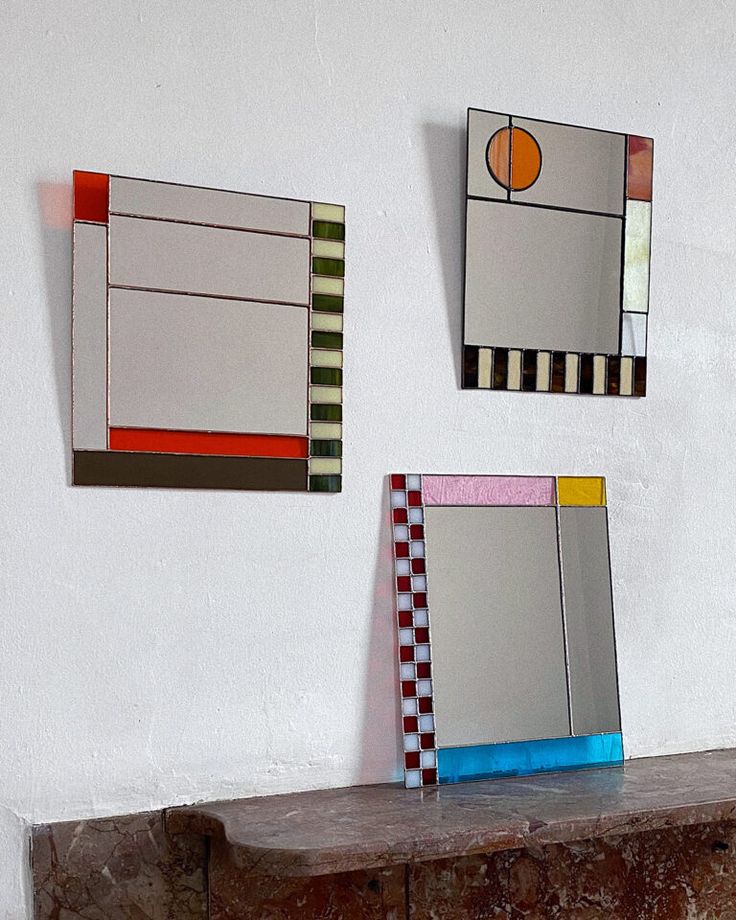 three mirrors on the wall with different shapes and sizes are hanging above a fireplace mantel