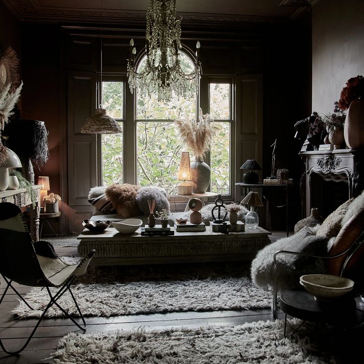 a living room filled with furniture and a chandelier hanging from the ceiling next to a window