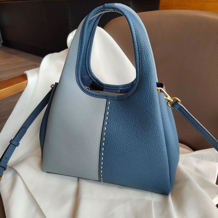 Indulge in luxury with this paneled handbag, crafted from genuine leather for a refined touch. Designed for women, it offers a casual style and has a spacious interior that includes an interior slot pocket and a cell phone pocket for organized storage. The hasp closure ensures both security and elegance. This handbag seamlessly combines sophisticated design with everyday functionality. Blue Rectangular Faux Leather Bag, Luxury Large Capacity Blue Satchel, Luxury Blue Bucket Bag With Double Handle, Blue Top Handle Bag With Leather Handles, Luxury Blue Hobo Bag With Top Handle, Luxury Blue Top Handle Hobo Bag, Leather Handheld Satchel For Errands, Luxury Faux Leather Shoulder Bag With Handles, Blue Leather Rectangular Satchel